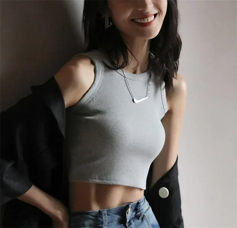 Woman wearing a gray sleeveless top and blue jeans with a blurred background