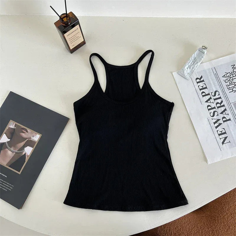 Black tank top on a white surface with a book and newspaper.