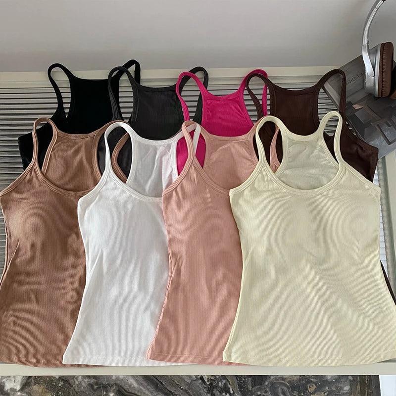 Row of various colored tank tops on a white surface.
