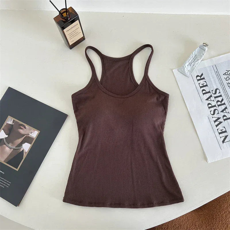 Brown tank top on a white surface with a book and newspaper.