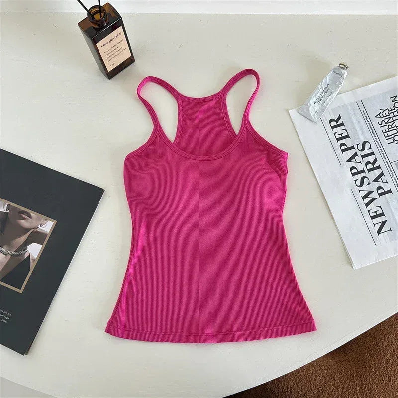 Pink tank top on a white surface with a book and newspaper.
