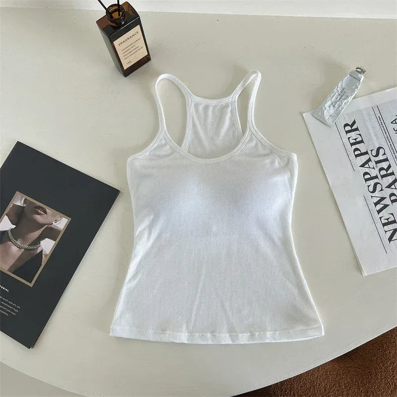 White tank top on a light surface with a magazine and bottle in the background