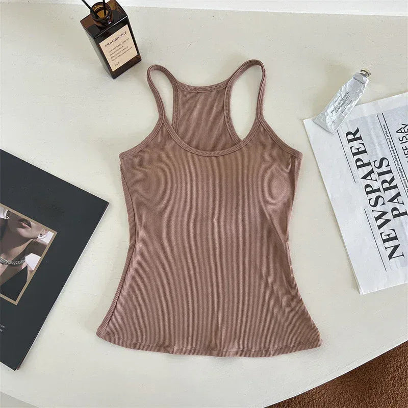 Brown tank top on a light surface with a book and newspaper.