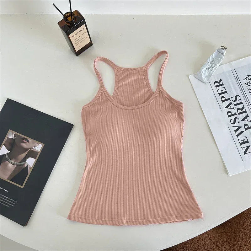 Pink tank top on a white surface with a magazine and bottle in the background