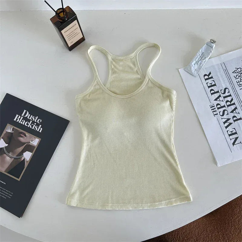 Light green tank top on a white surface with a book and newspaper.