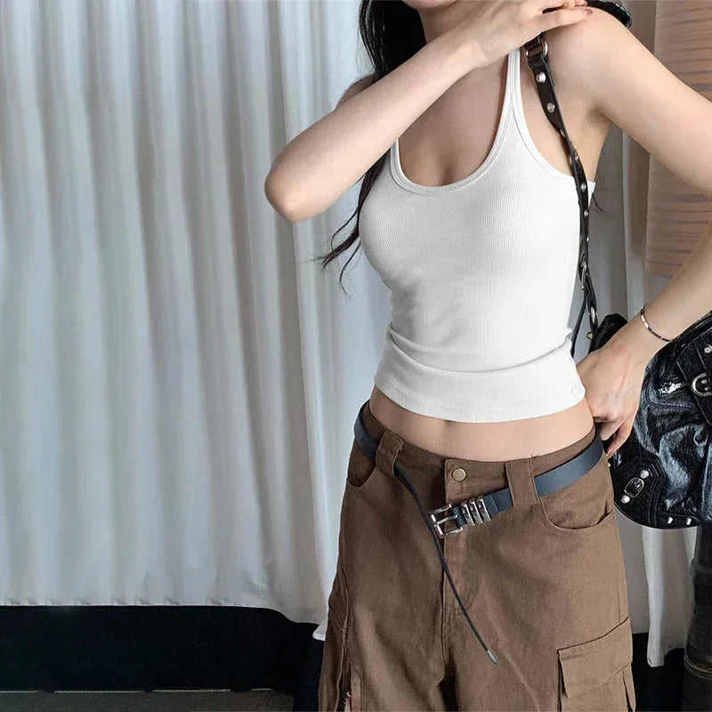 Person wearing a white tank top and brown pants with a black bag.
