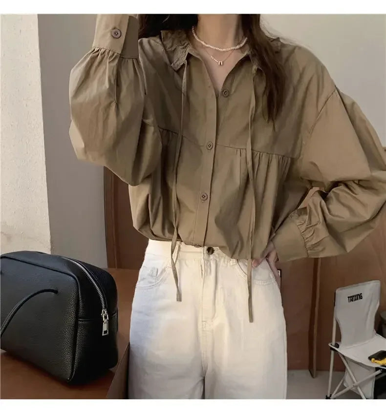 Person wearing a beige shirt and white pants with a black bag in the background
