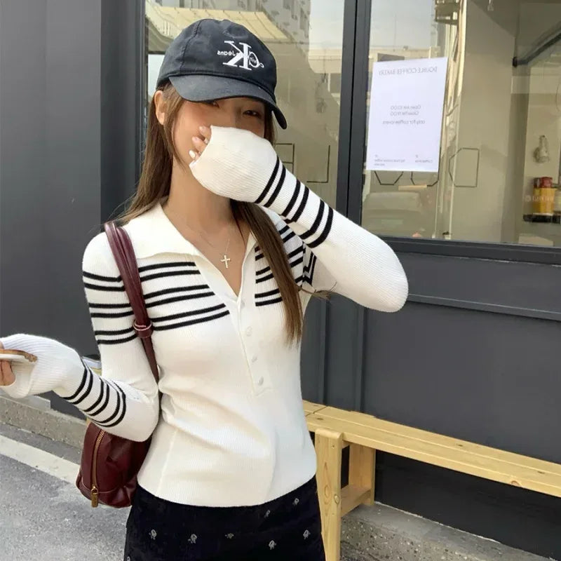 Person wearing a striped shirt, cap, and gloves, holding a mask in front of their face.