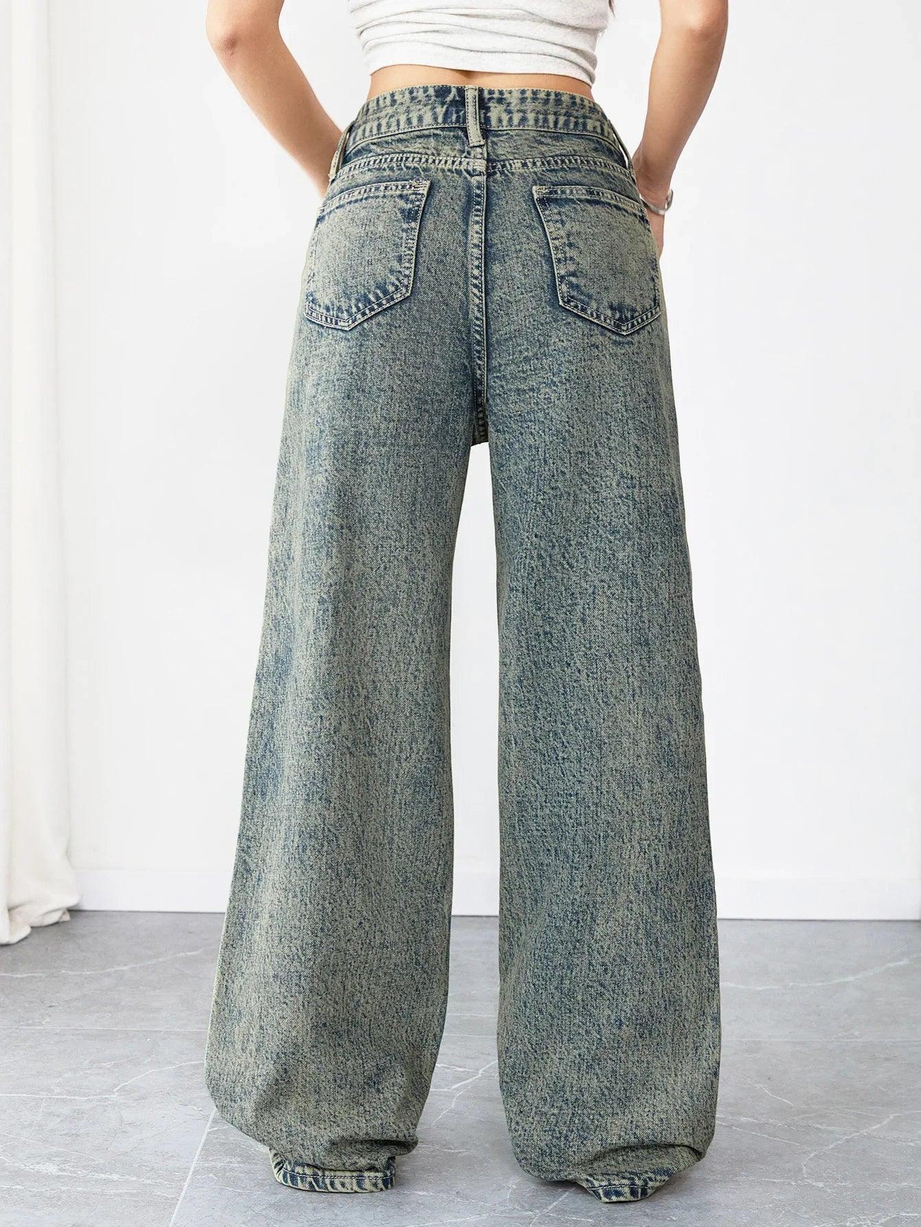 Person wearing wide-leg acid-wash jeans on a plain background