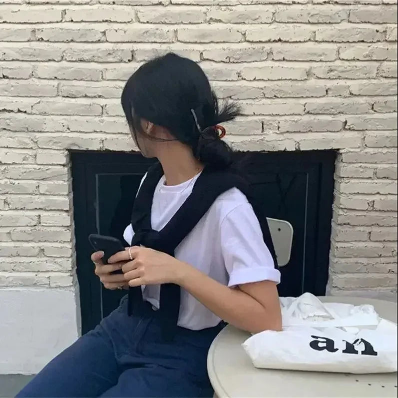 Person sitting on a bench using a phone with a white brick wall background