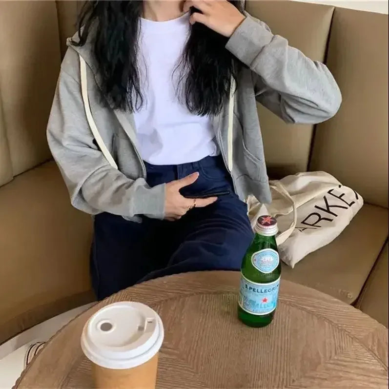 Person sitting on a couch with a bottle and cup on a table in front of them