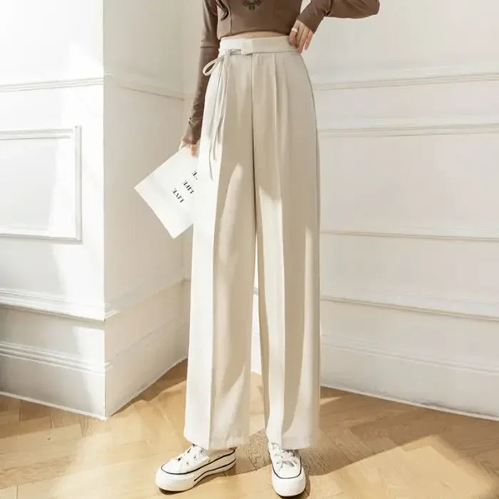 Person wearing beige wide-leg pants and a brown top in a minimalistic room.