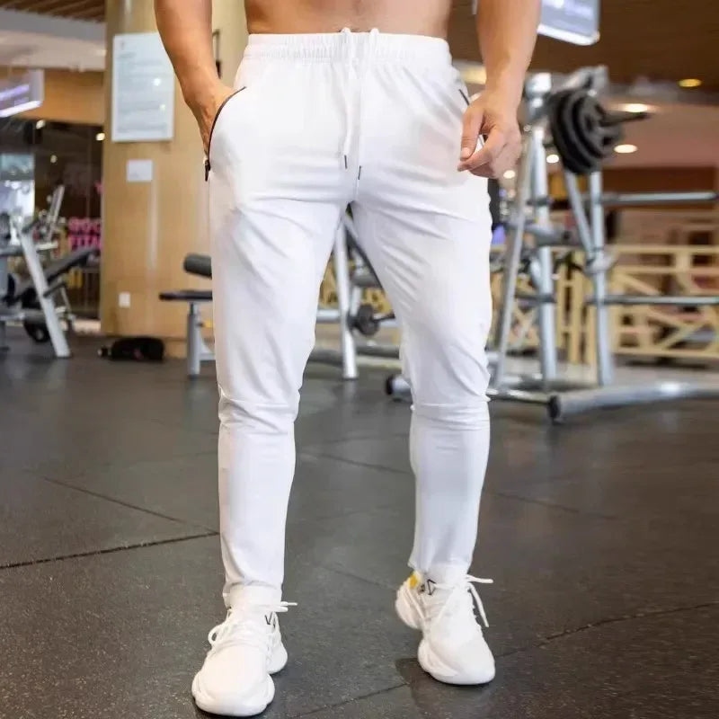 Person wearing white jogger pants and white sneakers in a gym setting