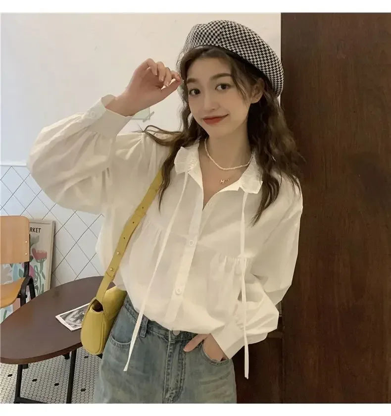 Woman wearing a white shirt, checkered hat, and jeans indoors.