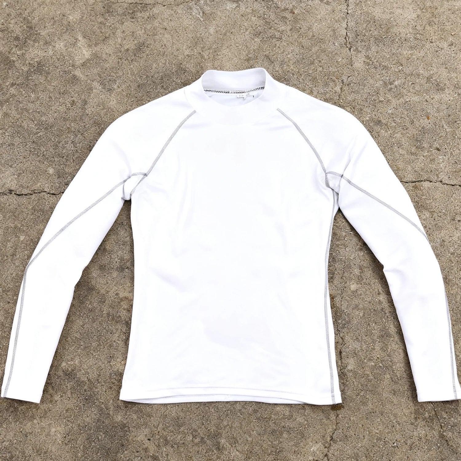 White long-sleeve shirt on a textured beige surface