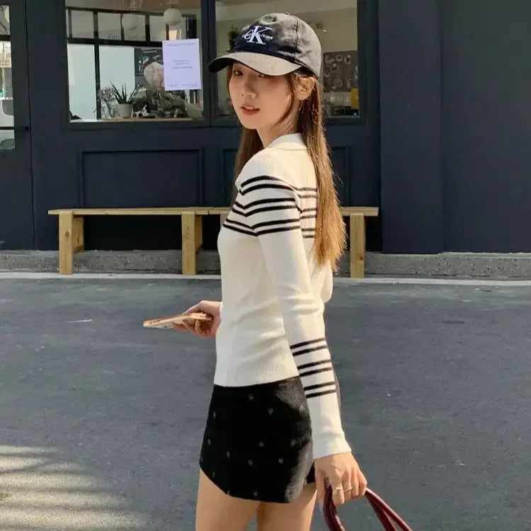 Woman wearing a striped sweater and cap, standing on a street.