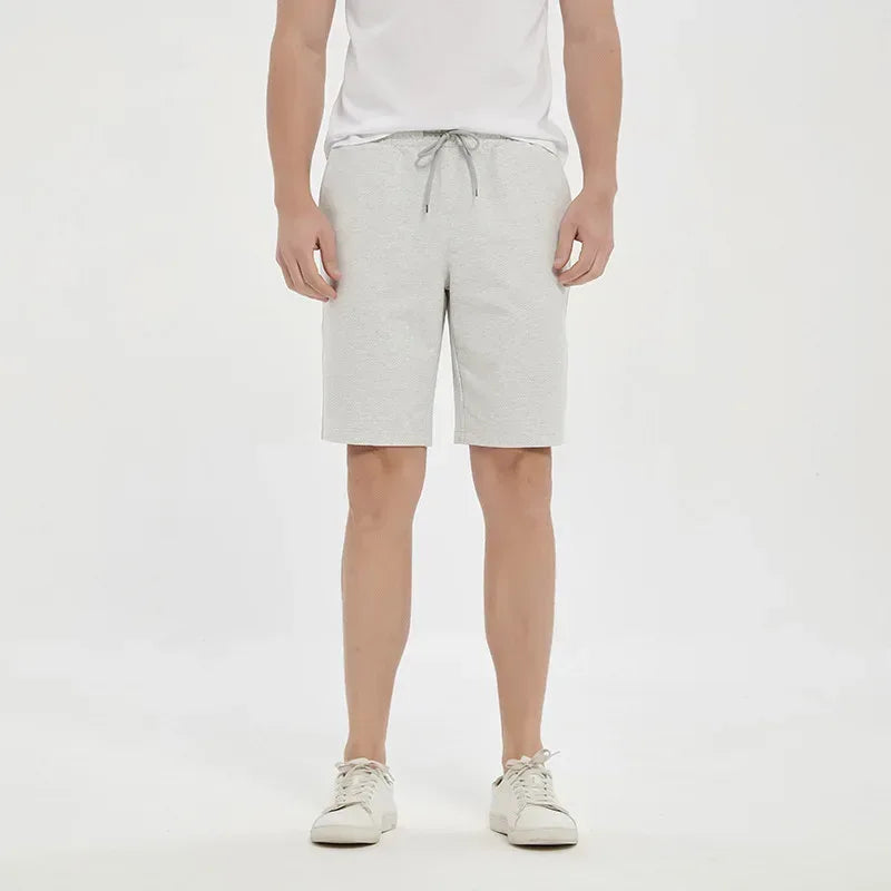 Person wearing light gray shorts on a white background
