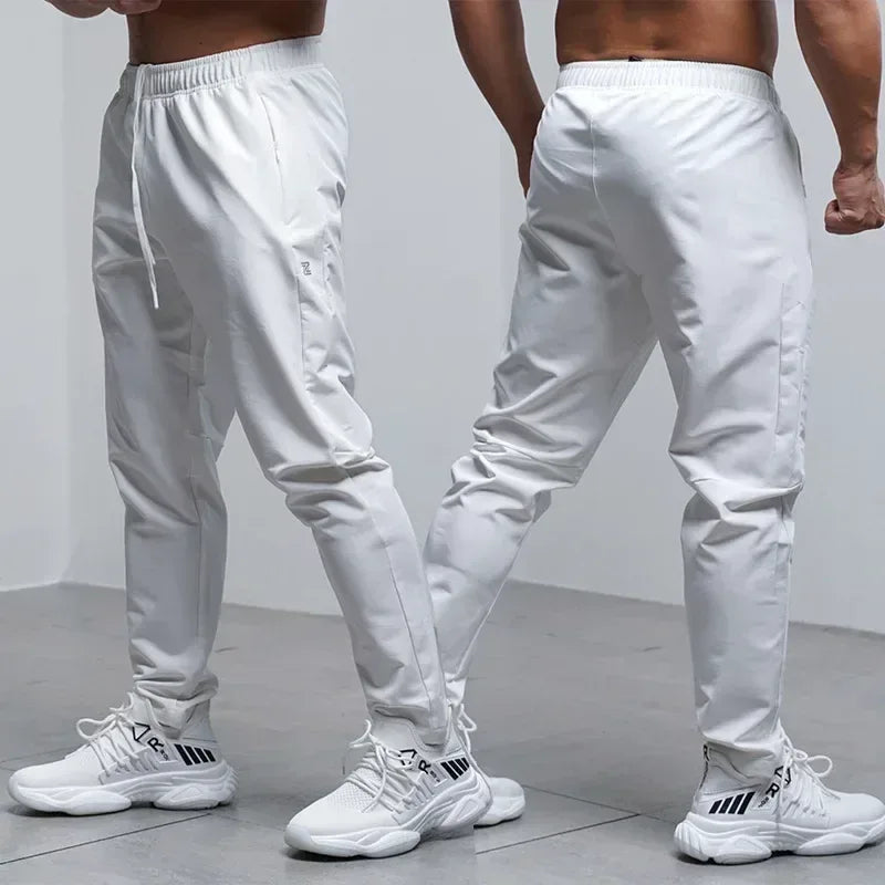 Two pairs of white jogger pants worn by a person on a plain background
