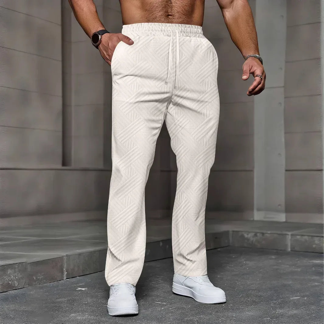 Person wearing white textured pants standing against a gray stone wall.