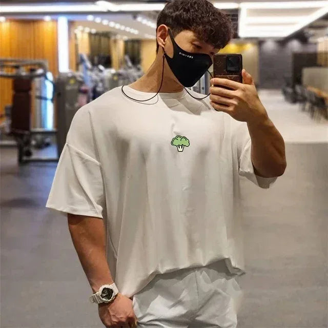 Person wearing a white t-shirt with a logo, taking a mirror selfie in an indoor setting.