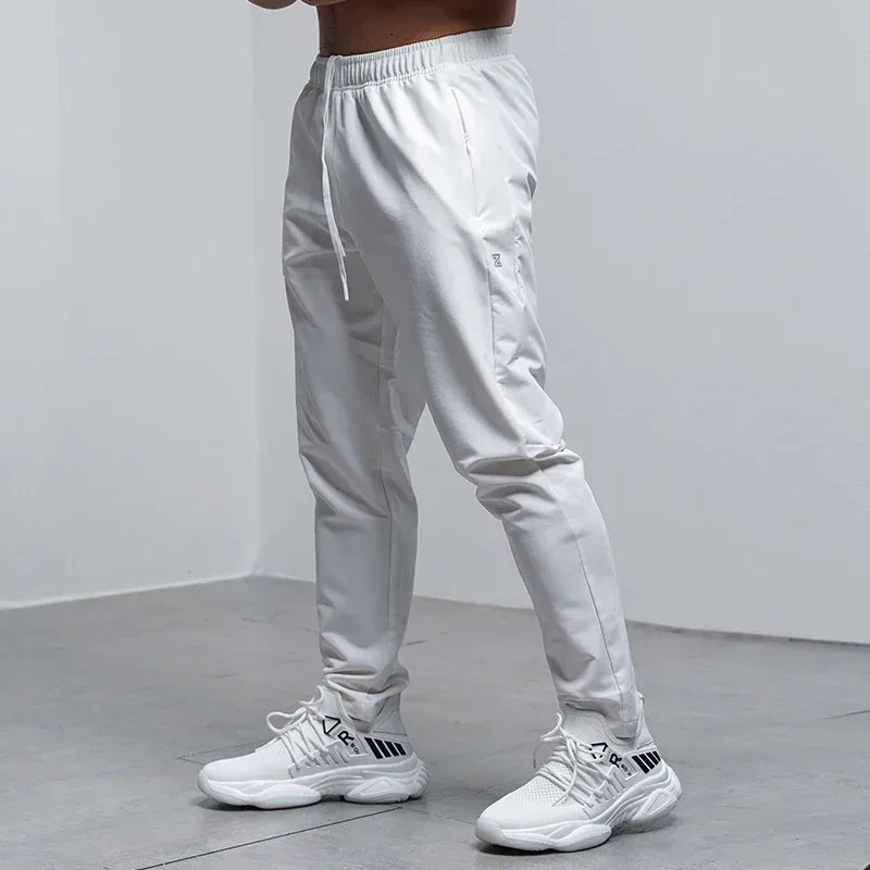 Person wearing white jogger pants and white sneakers on a plain background