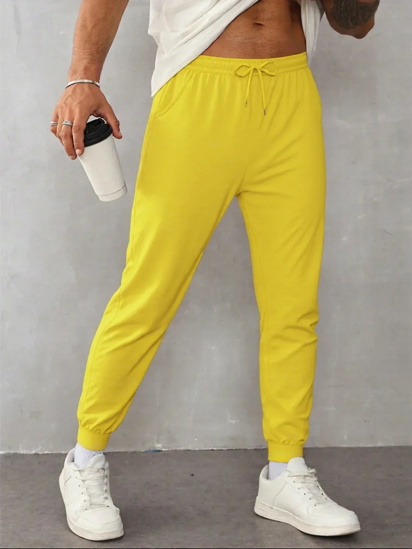 Person wearing bright yellow jogger pants with a plain background